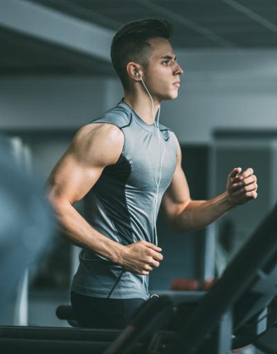 Young man running on a treadmill with earphones