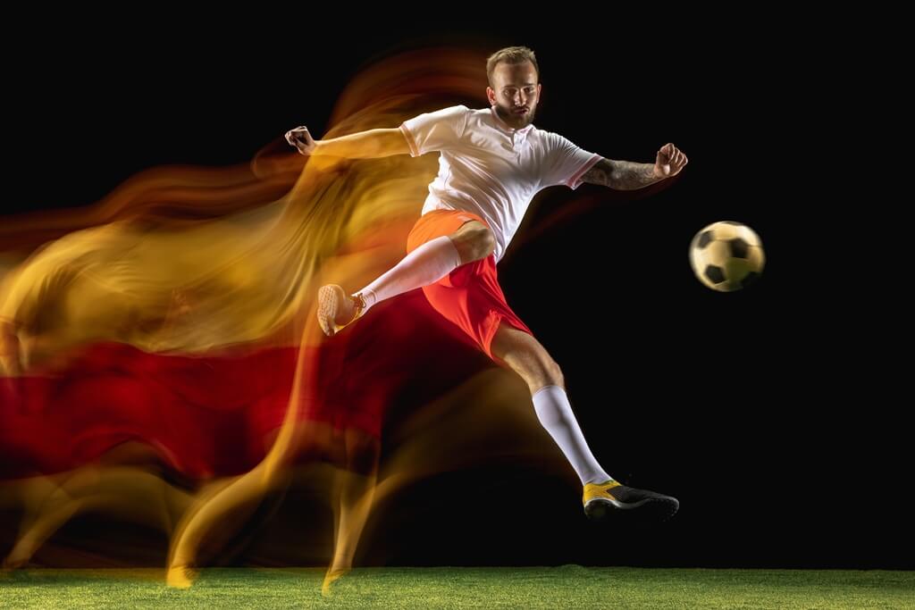 serious elderly doctor holds a soccer ball in one hand and points