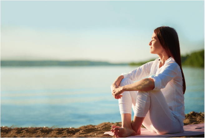 Young woman sitting on the beach and meditating