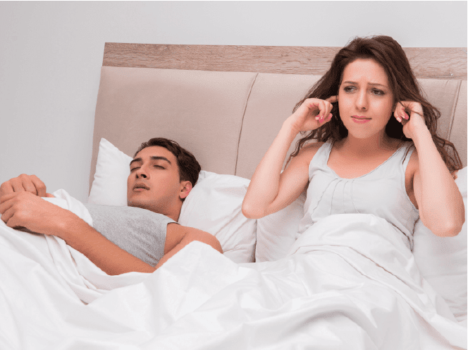 Young couple in bed - wife can not sleep because of husband's snoring