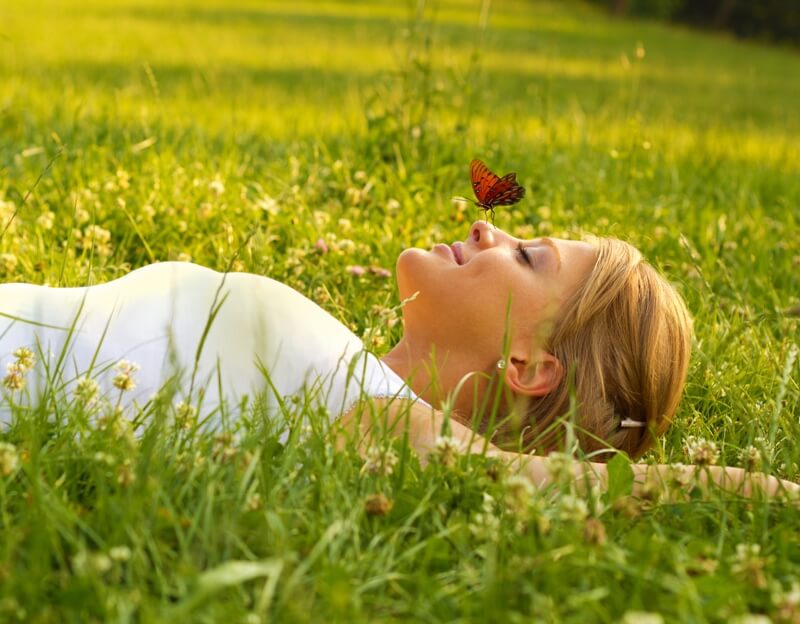 Girl lying on the grass and butterfly landing on her nose
