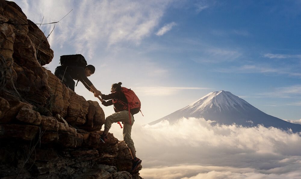 two persons climbing together on the mountain