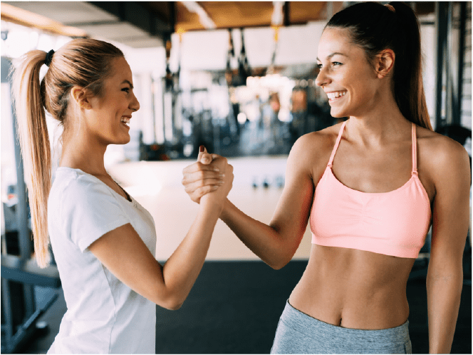 Two girls in the gym smiling and shaking hands